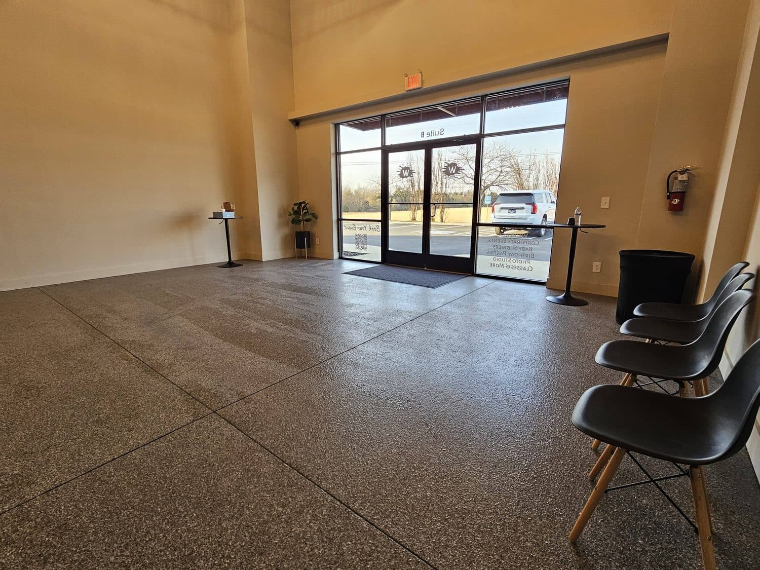 The glass storefront at the front of the room, daylight coming in across a polished concrete floor